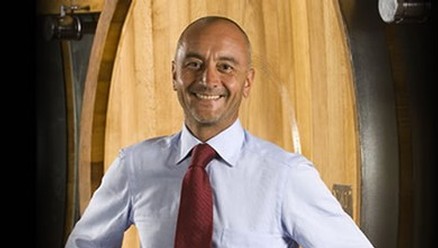 Winemaker Marco Galeazzo dressed in a tie standing in front of an oak barrel